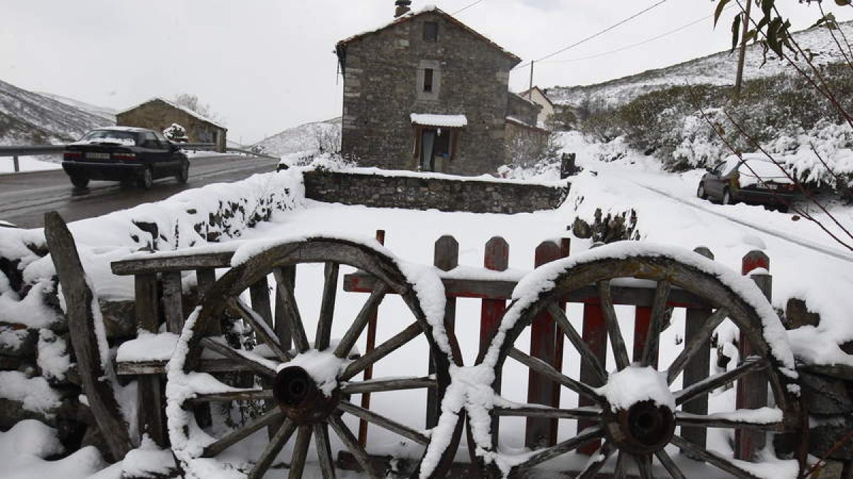 Un vehículo circula rodeado de nieve por las inmediaciones de Puebla de Lillo.