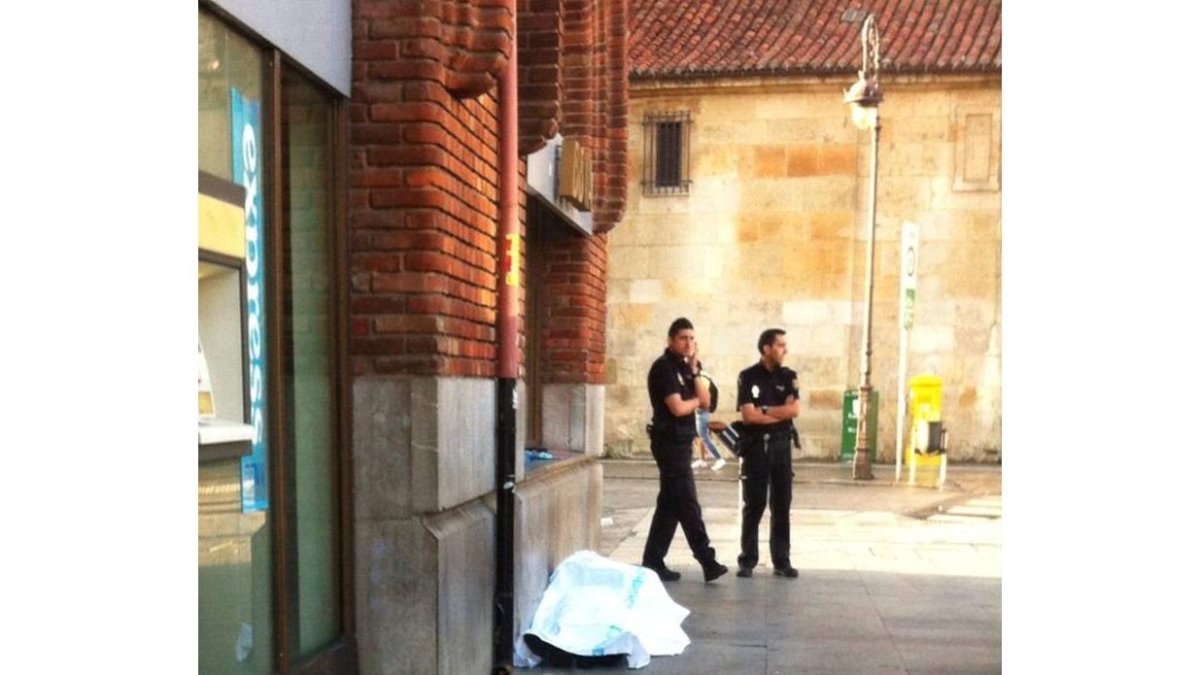 Efectivos de la Policía Nacional junto al cuerpo sin vida del mendigo hallado en la Plaza de Santo Domingo.