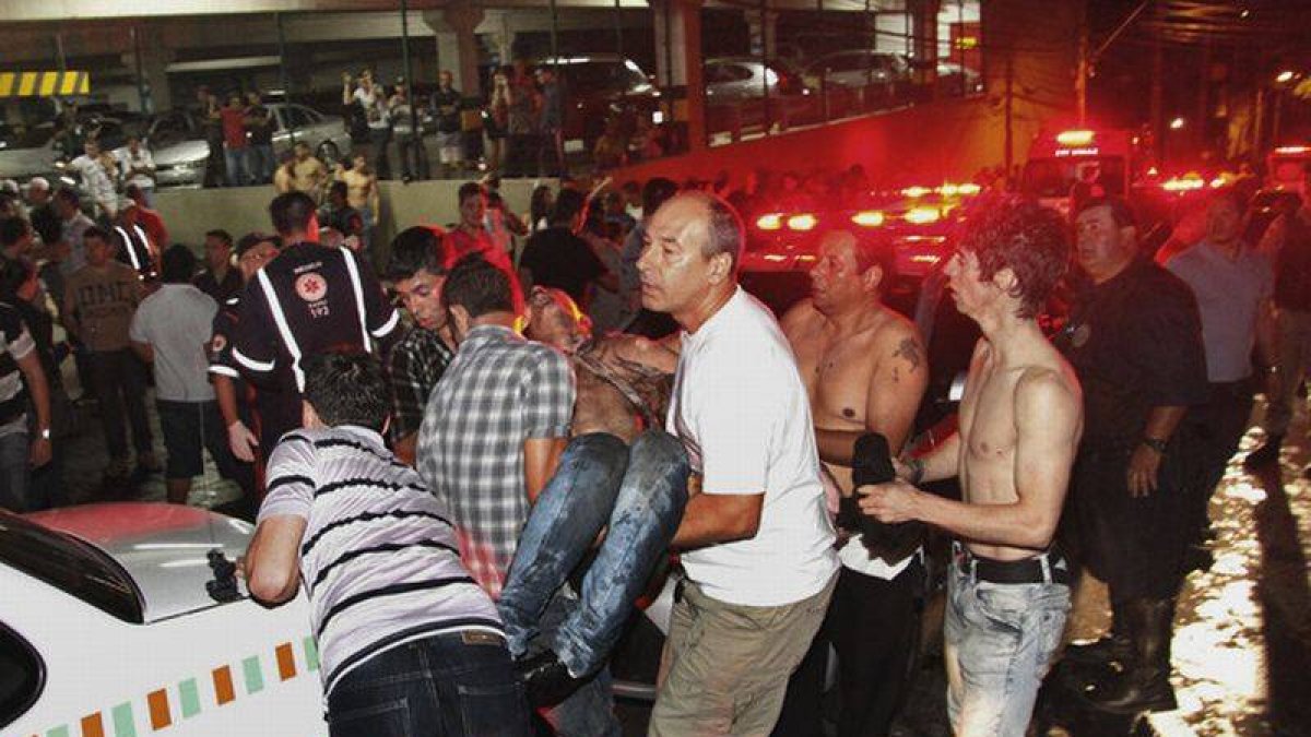 Un grupo de personas trasladan a una víctima del incendio de la discoteca Kiss, en Santa Maria (Brasil) este domingo.