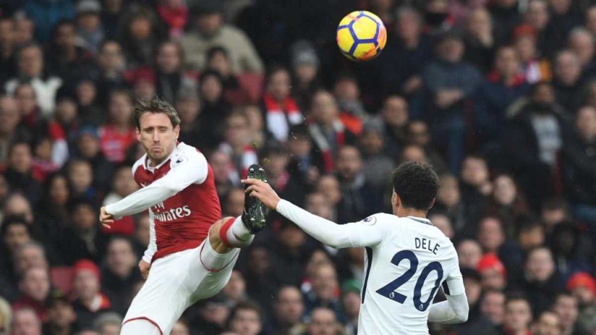 Laurent Koscielny despeja un balón ante la presencia de Dele Alli.