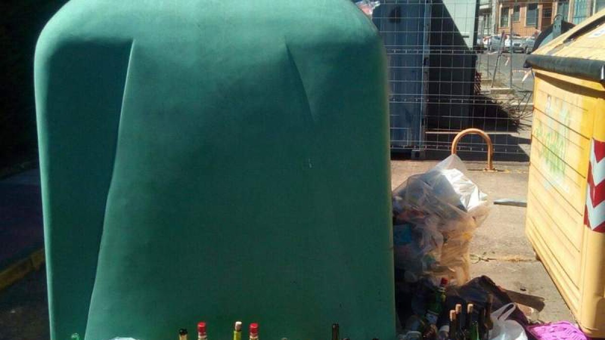 Botellas fuera de los contenedores de reciclaje de vidrio. DL