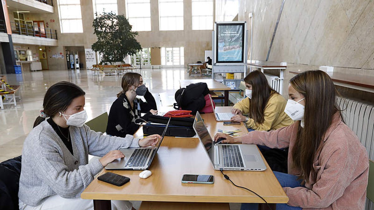 Alumnas de la Universidad de León trabajan con sus ordenadores en una de las mesas del vestíbulo de la Facultad de Económicas y Empresariales. MARCIANO PÉREZ