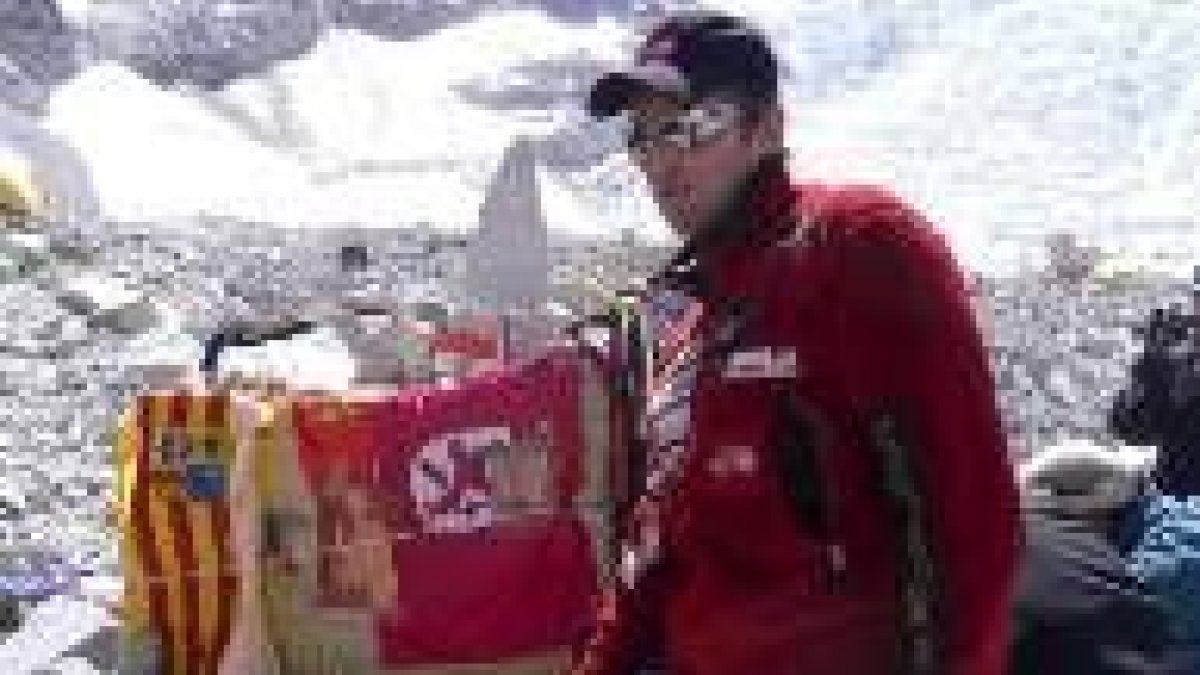 Jesús Calleja delante de una de las ofrendas en el campo base con la bandera de León