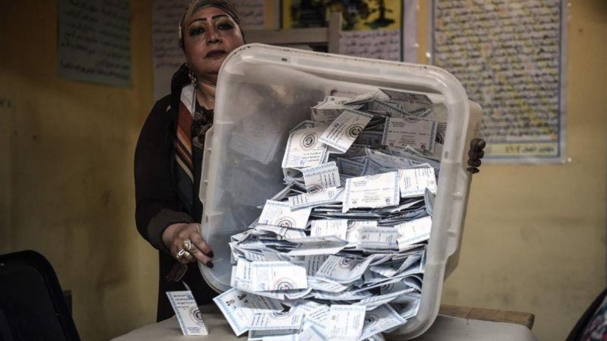 Una miembro de una mesa electoral muestra las papeletas depositadas en una urna en El Cairo.