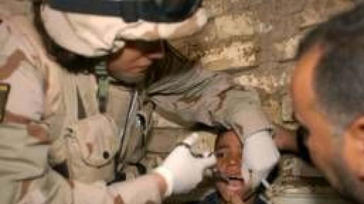 Una dentista-soldado nicaragüense de la Plus Ultra extrae una muela a un niño iraquí