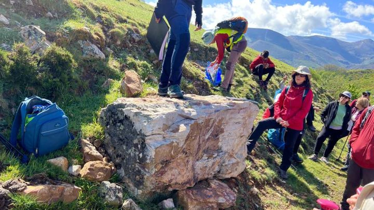 Rodrigo Castaño sobre la piedra más antigua de Babia, una cuarcita de 490 millones de años que está a simple vista, al borde del camino que conduce desde el pueblo de La Riera a la majada de Fonfría, una ruta que permite descubrir el nacimiento de Babia y la formación de la Tierra en apenas cuatro kilómetros, en los que se recorren varias eras. Junto a Castaño, participantes en Geolodía, una jornada divulgativa que  organiza todos los años el Instituto Geológico y Minero de España, Igme. S. VERGARA PEDREIRA