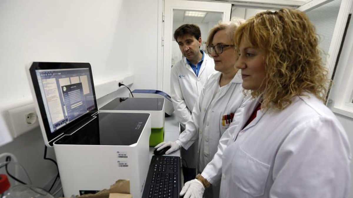 Emiliano Honrado, Engracia Santín y Cristina Díez, delante de uno de los aparatos que se utilizan para los análisis de biopsia líquida.