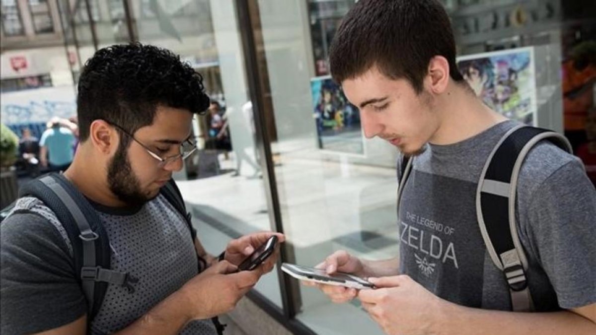Dos jóvenes usando la nueva aplicación para móviles Pokémon Go.