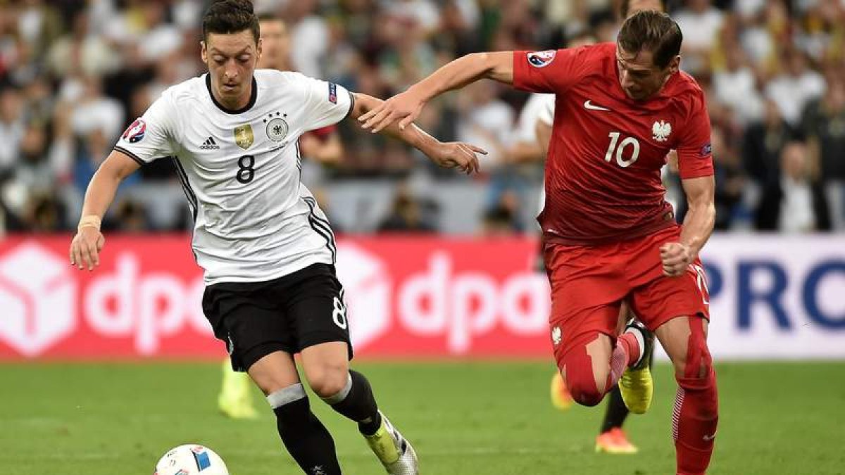 El delantero alemán Ozil intenta escaparse de la marca de un defensa polaco. CRISTOPHE