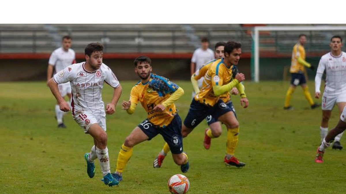 El leonés Abel se lleva un balón a pesar de la oposición de un jugador abulense. FERNANDO OTERO