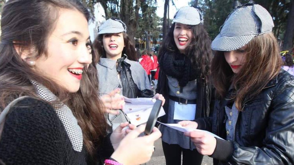 Un grupo de jóvenes disfrazadas de Sherlock Holmes, durante el juego, investigan con su lupa la lista de 33 pistas.