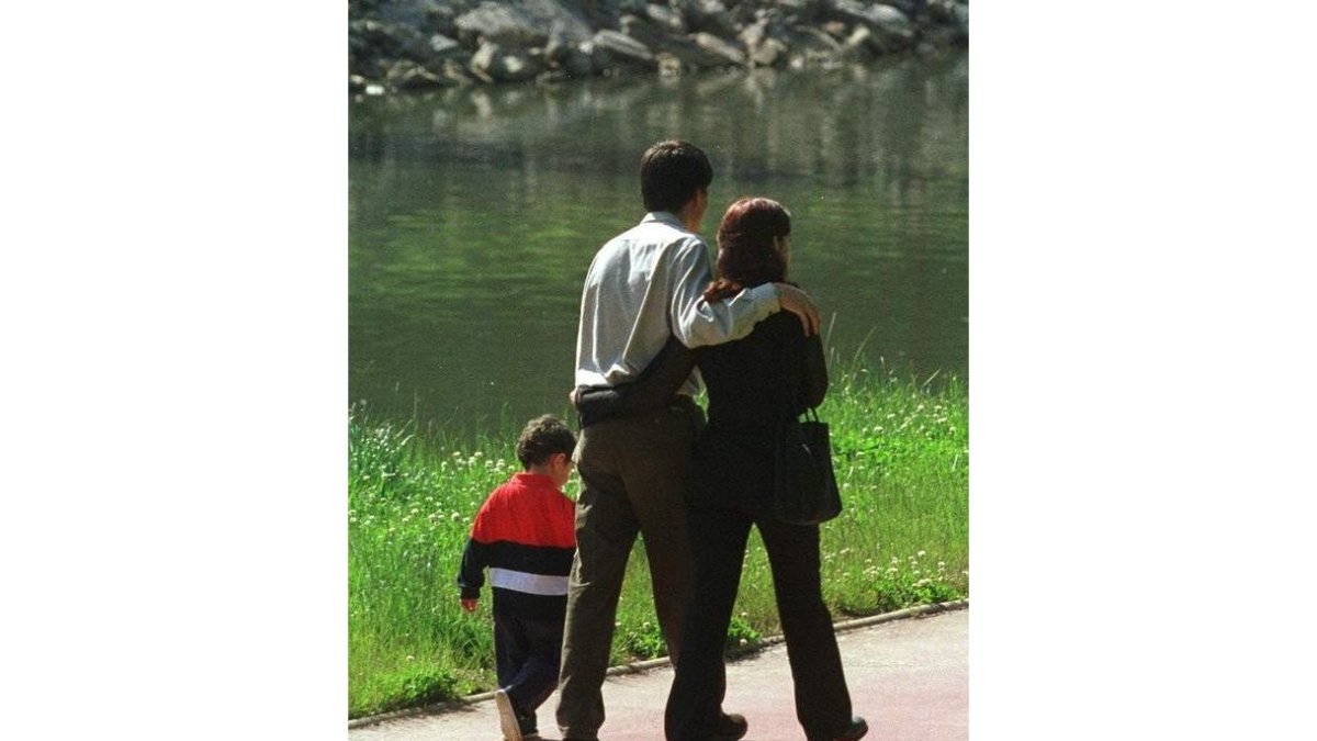 Una pareja pasea con su hijo por el paseo del río.