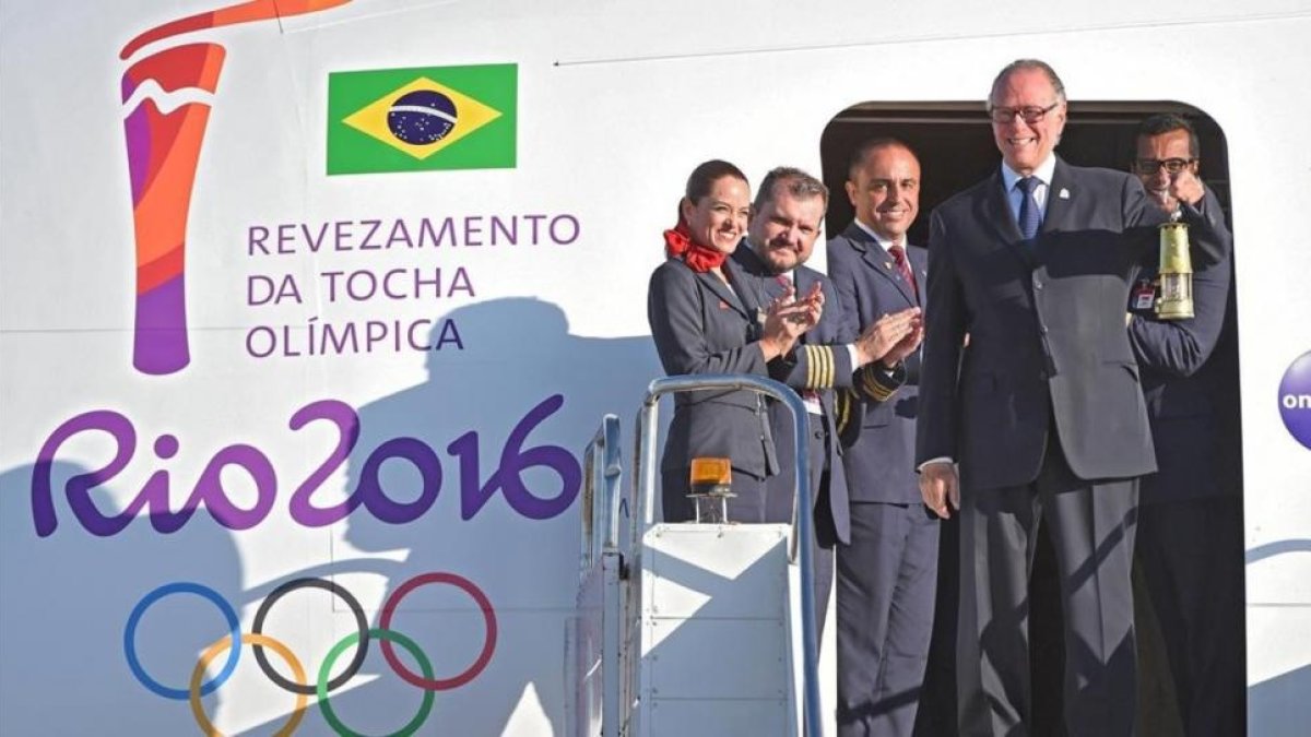 El presidente del Comite Olímpico Brasileño, Carlos Arthur Nuzman, transporta la linterna con el fuego olímpico a su llegada a Brasilia.