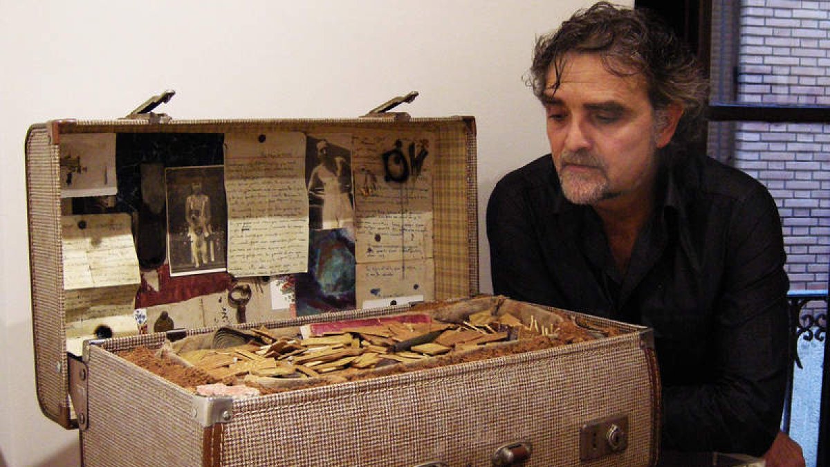 El artista Carlos España con la maleta en la que hay tierra de un cementerio leonés.