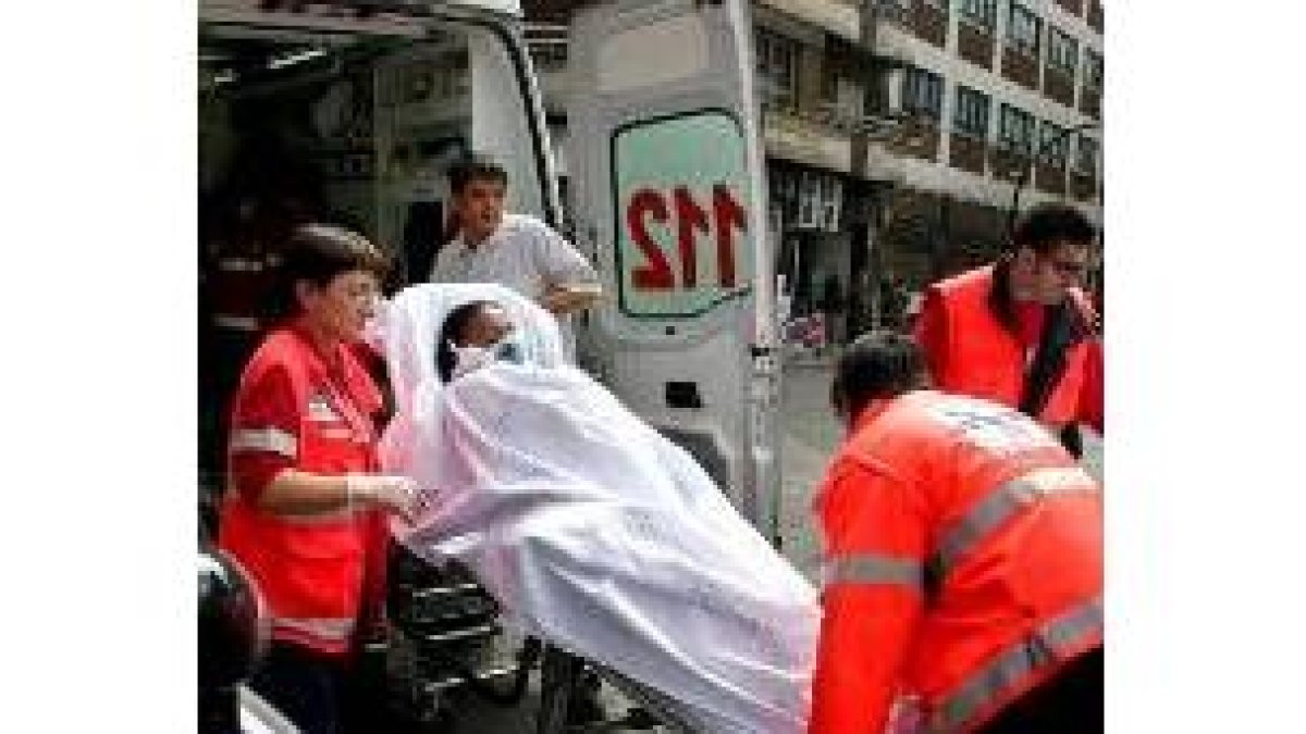 La inquilina del piso en el momento de ser evacuada por una ambulancia