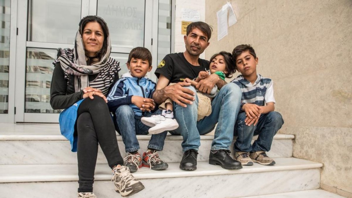 Osman, de siete años, en brazos de su padre con su madre y hermanos, en Idomeni.