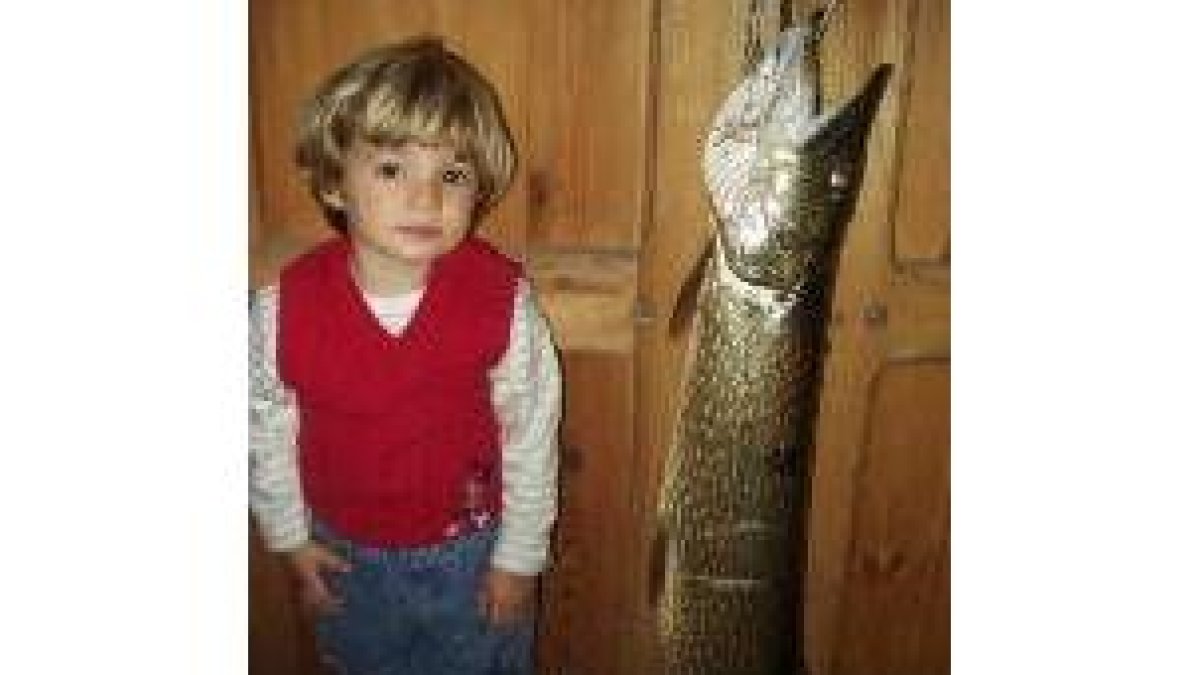 Un niño posa junto a una hembra de lucio recién desovada de 85 cm.