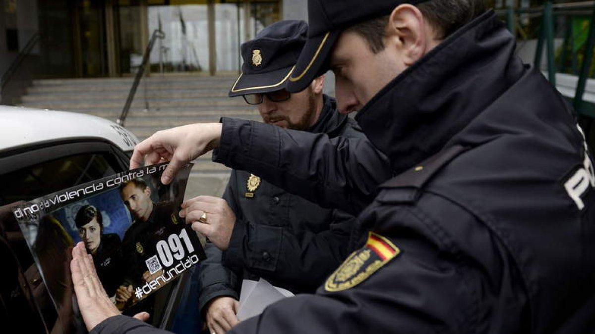 Dos policías colocan el cartel en uno de los coches que participan en esta campaña