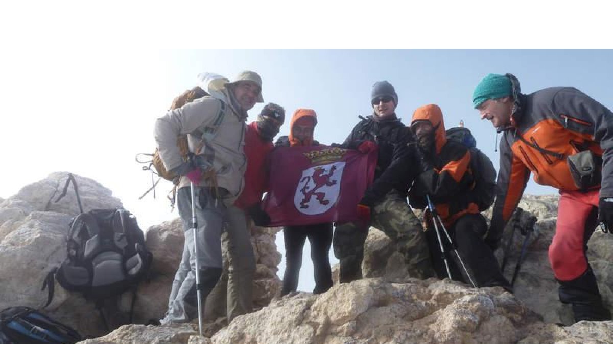 Coronando la cima de España con la bandera de la expedición leonesa.