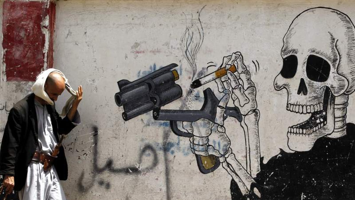 Un hombre camina junto a un grafiti antitabaco en Saná (Yemen). YAHYA ARHAB