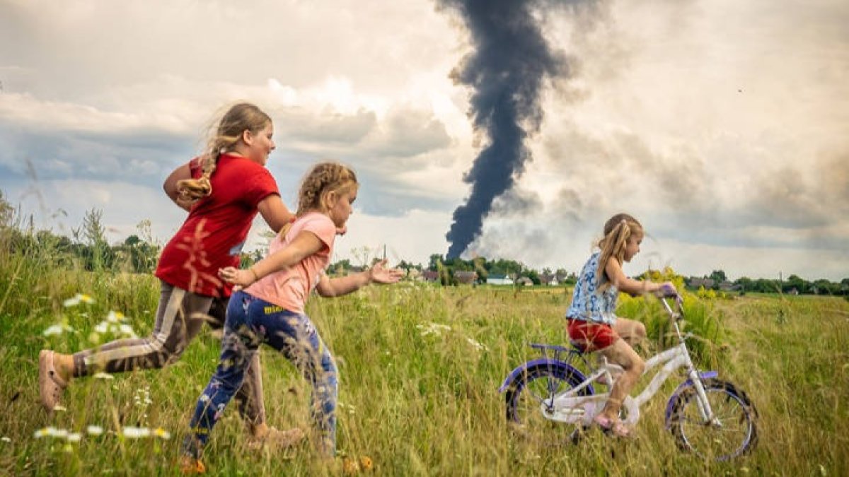 Una imagen de una niña en bicicleta junto a dos amigas en un prado en el noroeste de Ucrania, en