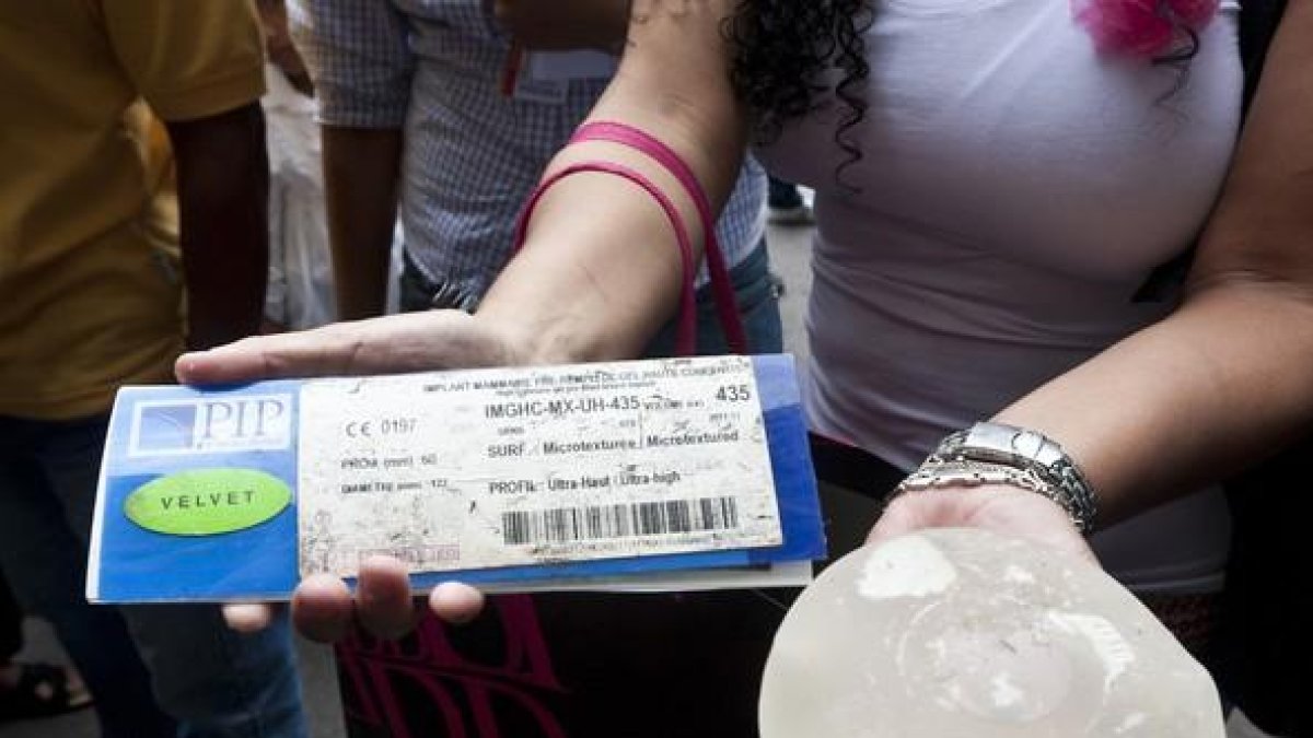 Una mujer sostiene unos implantes defectuosos de PIP.