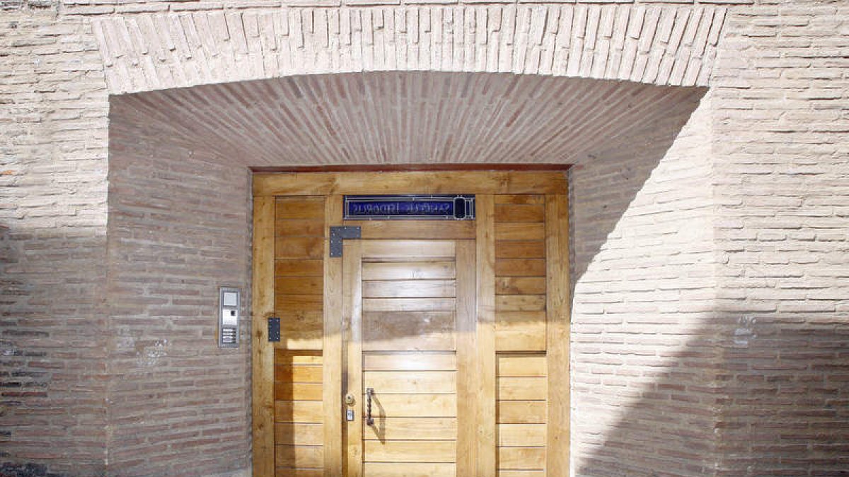 Puerta de acceso a San Isidoro, en la calle Sacramento de León; abajo, detalle de la vidriera del frontal de la puerta.
