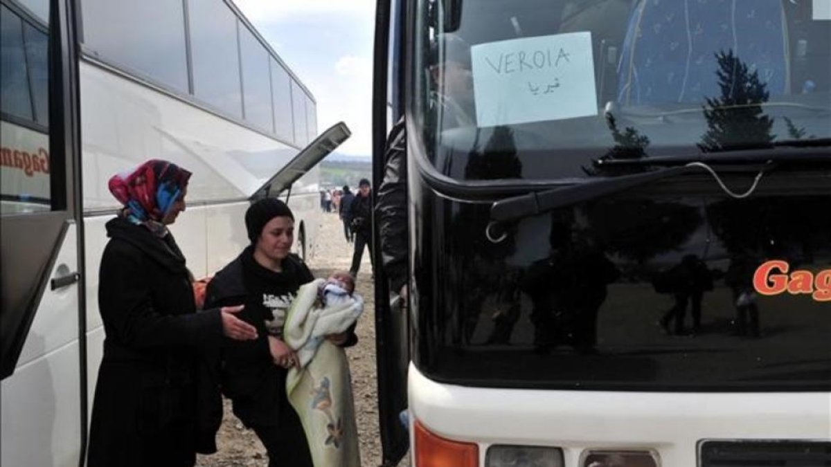 Dos mujeres se disponen a subir a un autocar en el campamento de Idomeni.