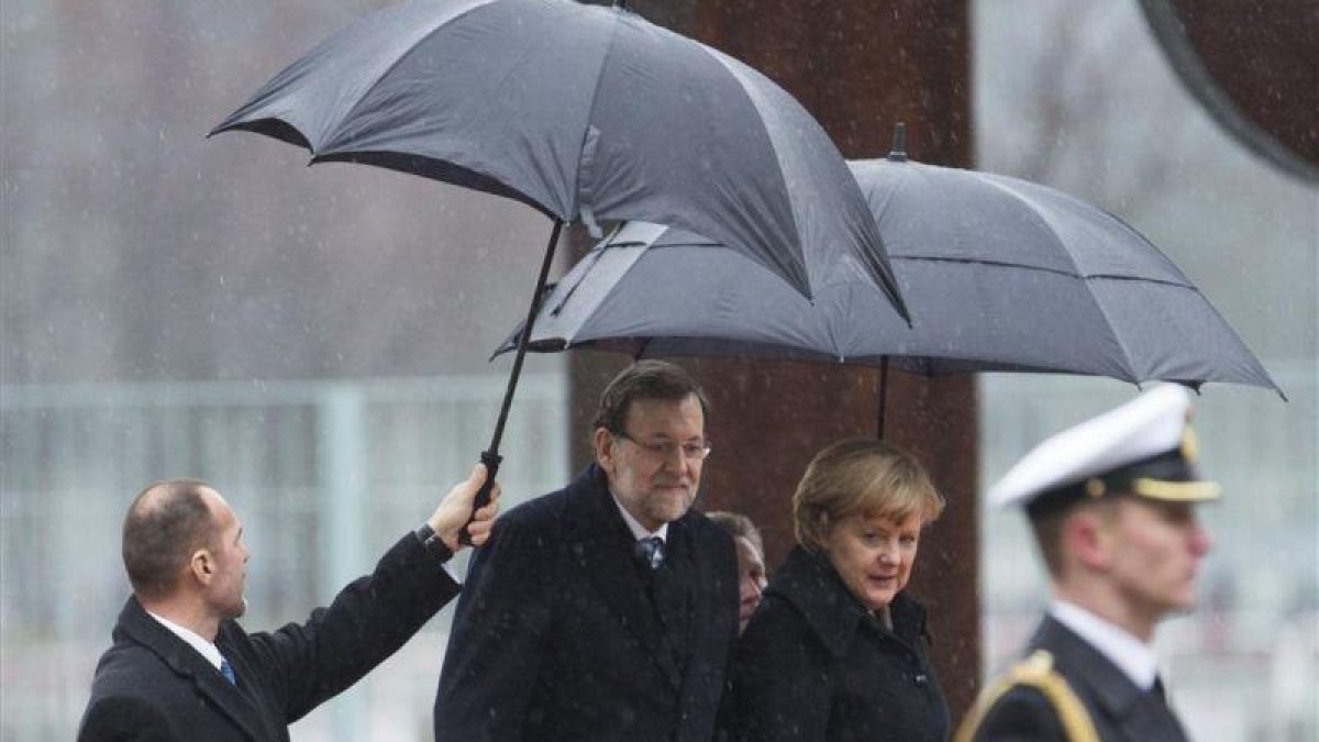 Mariano Rajoy y la cancillera alemana, Angela Merkel, en el 2013 en un día de lluvia en Berlín.