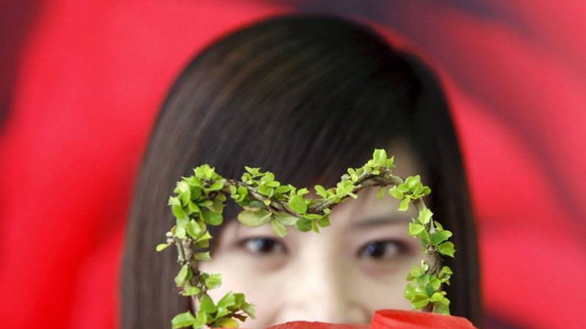 La joven Sutharat Thakaew muestra en Bangkok la planta con forma de corazón que vende para promover regalos florales de este tipo en fechas señaladas.