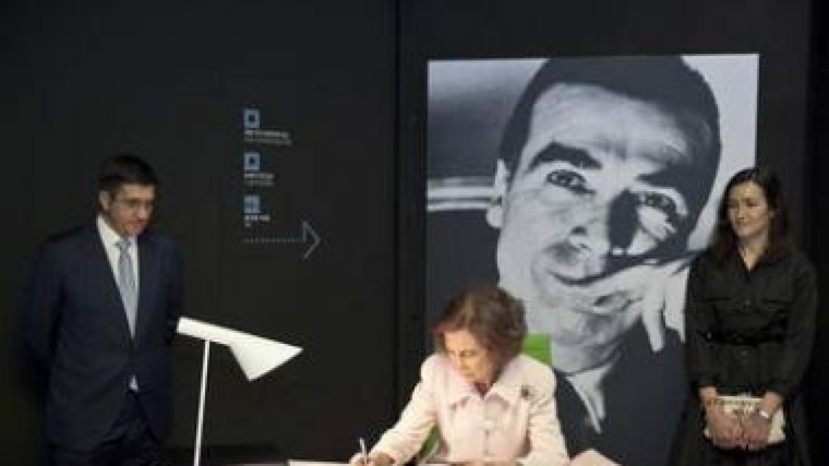 La reina firma en el libro de honor del museo escoltada por López y la ministra Sinde.