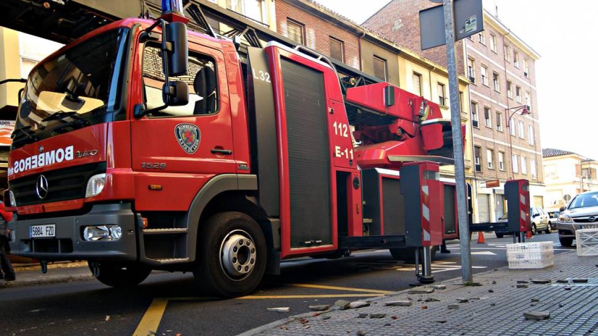Un camión del Parque de Bomberos de León junto a alguno de los fragmentos desprendidos de la cornisa.