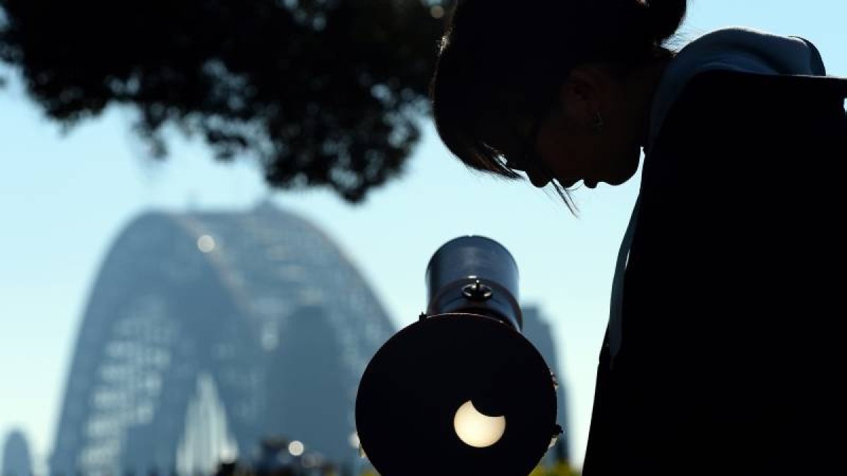 Una mujer ajusta un telescopio para observar el eclipse.