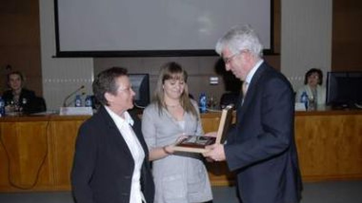 El rector de la Universidad le entrega una placa a la mujer y la hija de Rafael Rodríguez