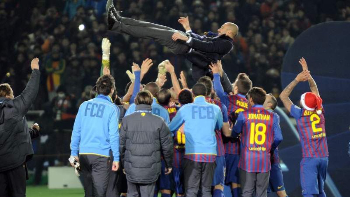Los jugadores del Barcelona mantean a su entrenador Pep Guardiola mientras celebran su victoria en la final del Mundial de Clubes contra el Santos.