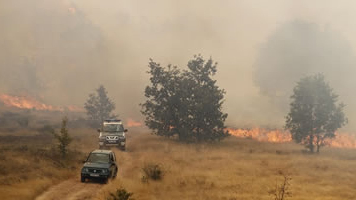 Vehículos de la Guardia Civil y de agentes forestales huyen de las llamas en Quintanilla.