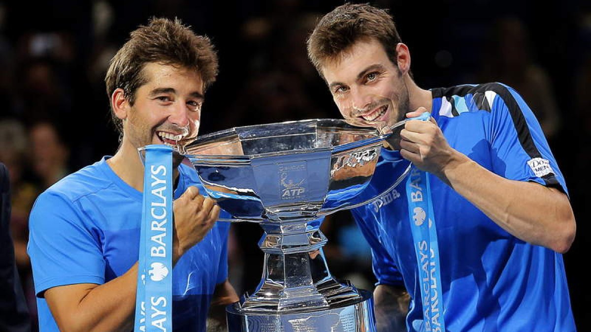 Marc López y Granollers muerden la copa que les acredita como campeones de dobles.