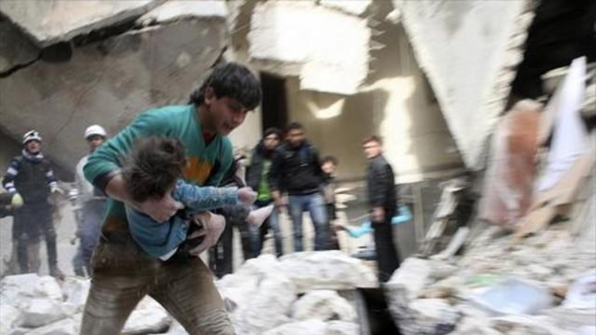 Un hombre traslada a una niña herida tras un bombardeo en Alepo.