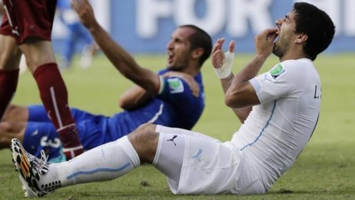 Suárez se toca los dientes mientras Chiellini se toca el hombro lastimado.