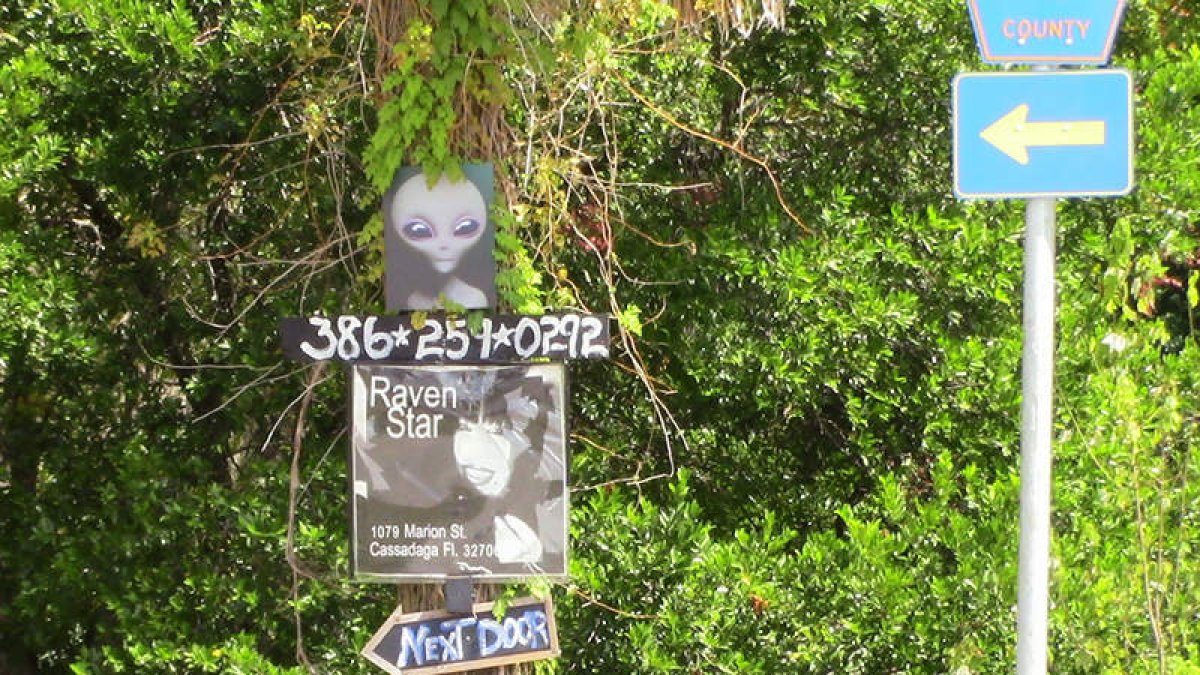 La figura de un alienígena y un cartel ofreciendo servicios de espiritismo en una de las calles de Cassadaga, en el condado Volusia, en el centro de Florida.