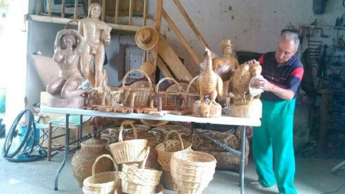 El artesano Vicente Robles Campillo posa junto a todas sus tallas realizadas con los troncos que se encuentra.