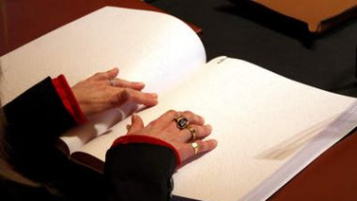 Una invidente lee el último libro sobre Botines editado en braille por Caja España.
