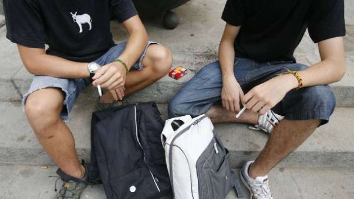 Dos adolescentes de 15 años fumando un cigarrilo.