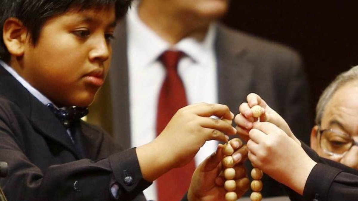 Dos niños ensartan las bolas de los números premiados de la Lotería de Navidad 2016.