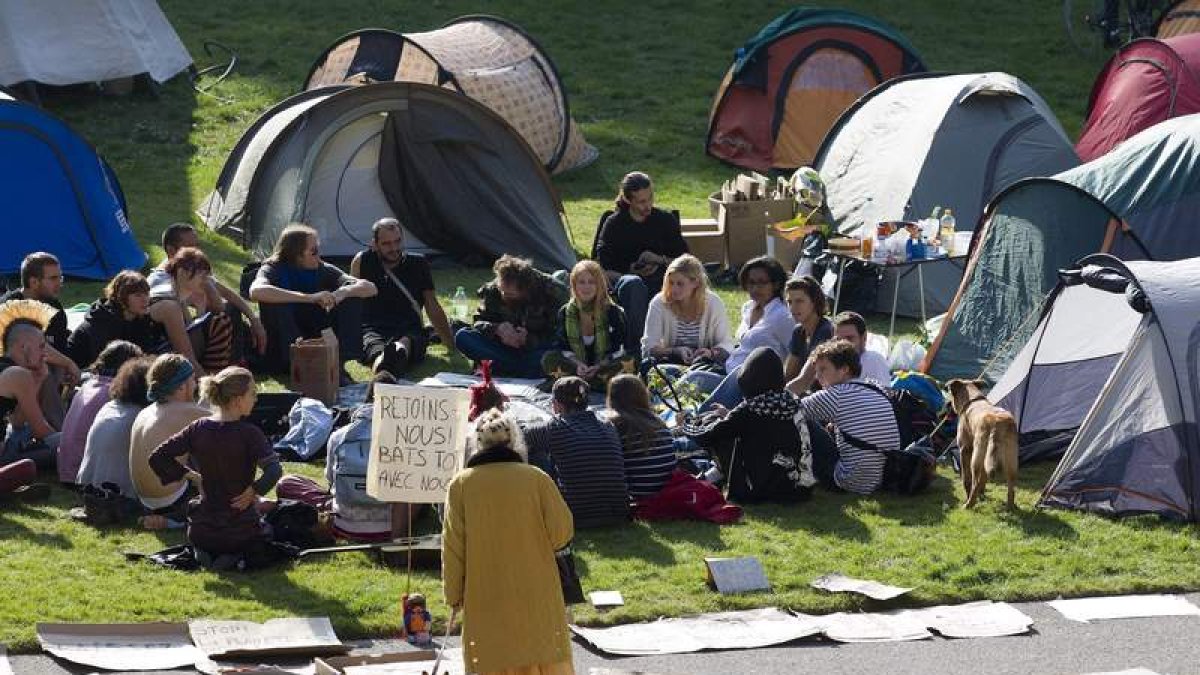 Una mujer mira a un grupo de ‘indignados’ en un campamento en Ginebra, Suiza.