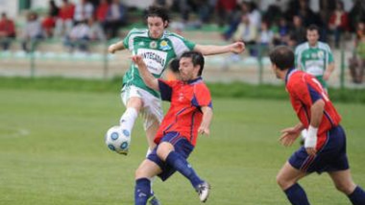 El delantero del Astorga Boni golpea el balón ante la oposición de un defensor de La Granja.