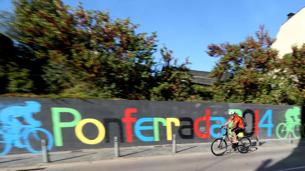 Un graffiti recuerda en la avenida del Castillo que Ponferrada acogió el Mundial. Abajo, nadie miraba la prueba en el Café Museo.