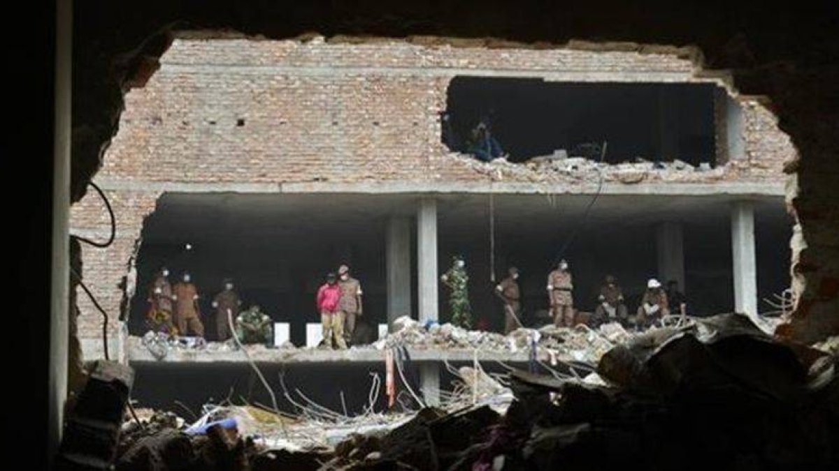 Miembros de los equipos de rescate observan los restos del edificio hundido en Savar, cerca de Dacca, este miércoles.