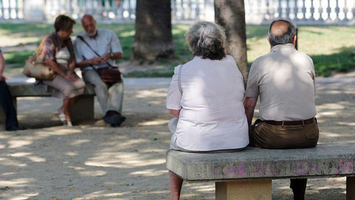 Personas mayores descansan en unos bancos de Barcelona.