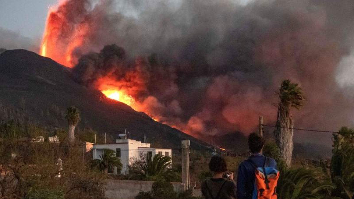 Unos caminantes observan y hacen fotos a la lava que sale del volcán. MIGUEL CALERO
